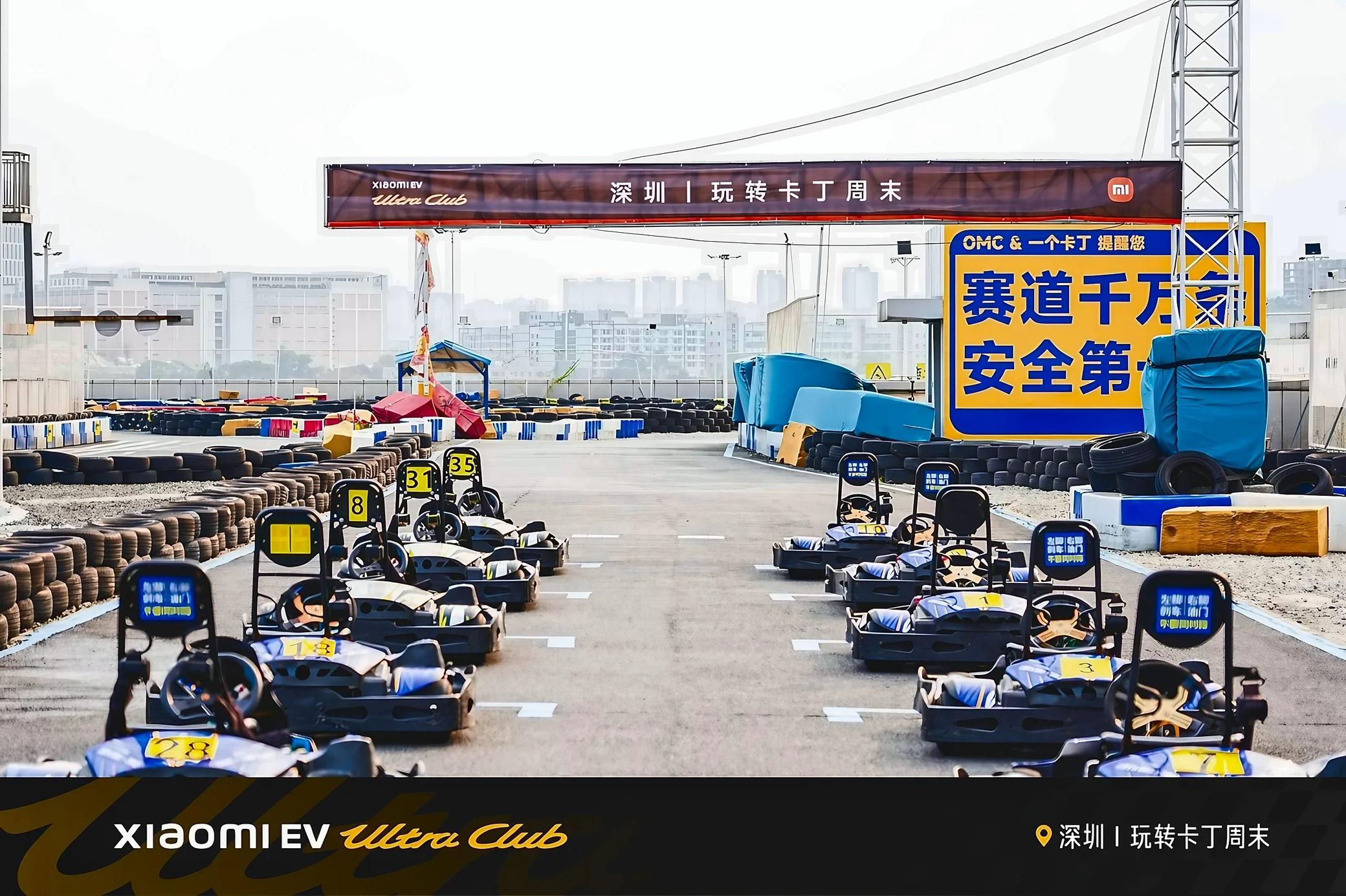 Two rows of empty go-karts line the starting grid beneath a Shenzhen event banner, surrounded by tire barriers and safety signage.