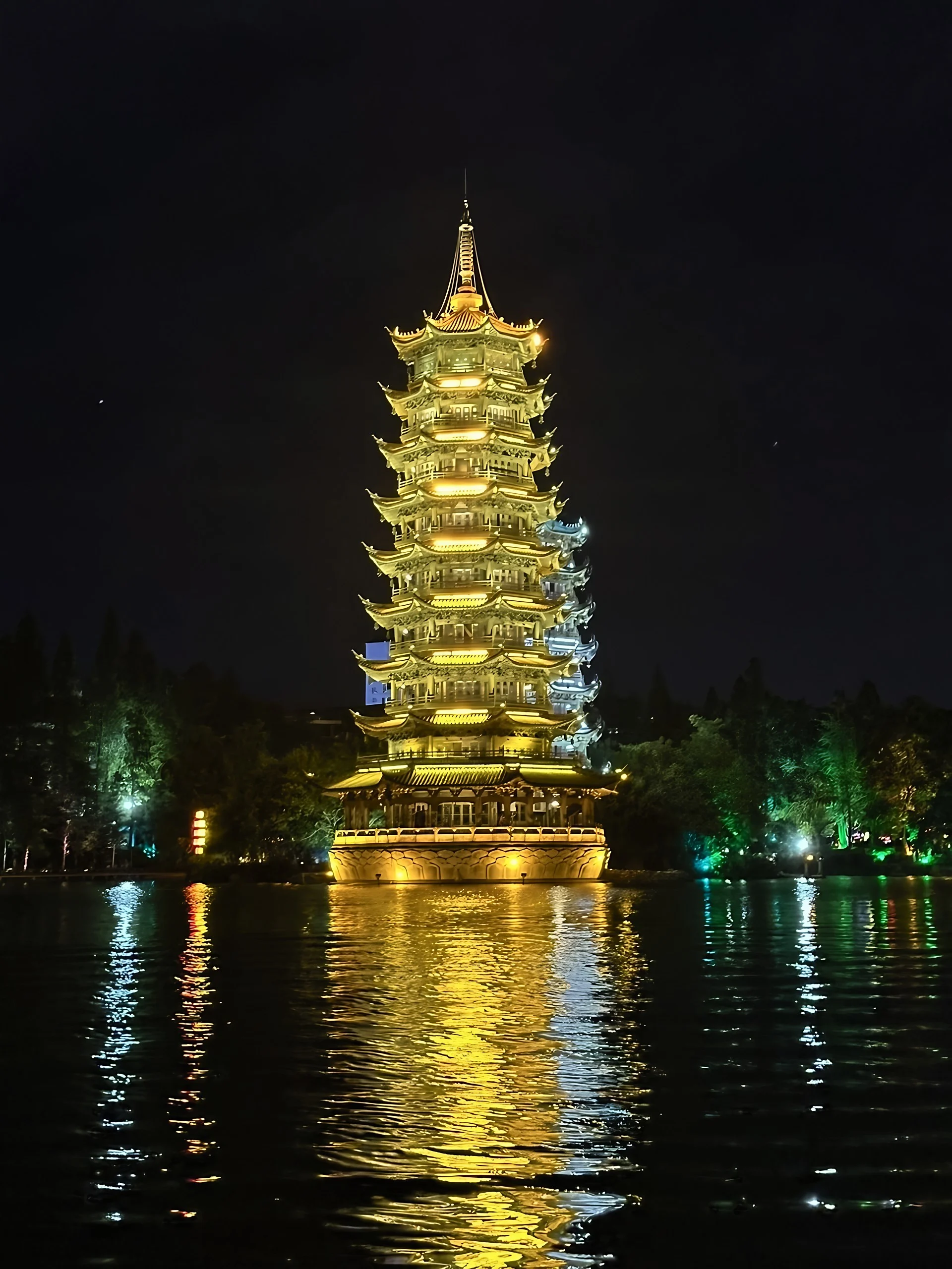 Guilin’s illuminated Sun and Moon Pagodas rise beside the lake, casting golden and silver reflections across the rippling water.